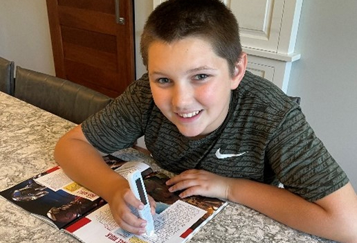 5th grader smiling while using C-pen in magazine.