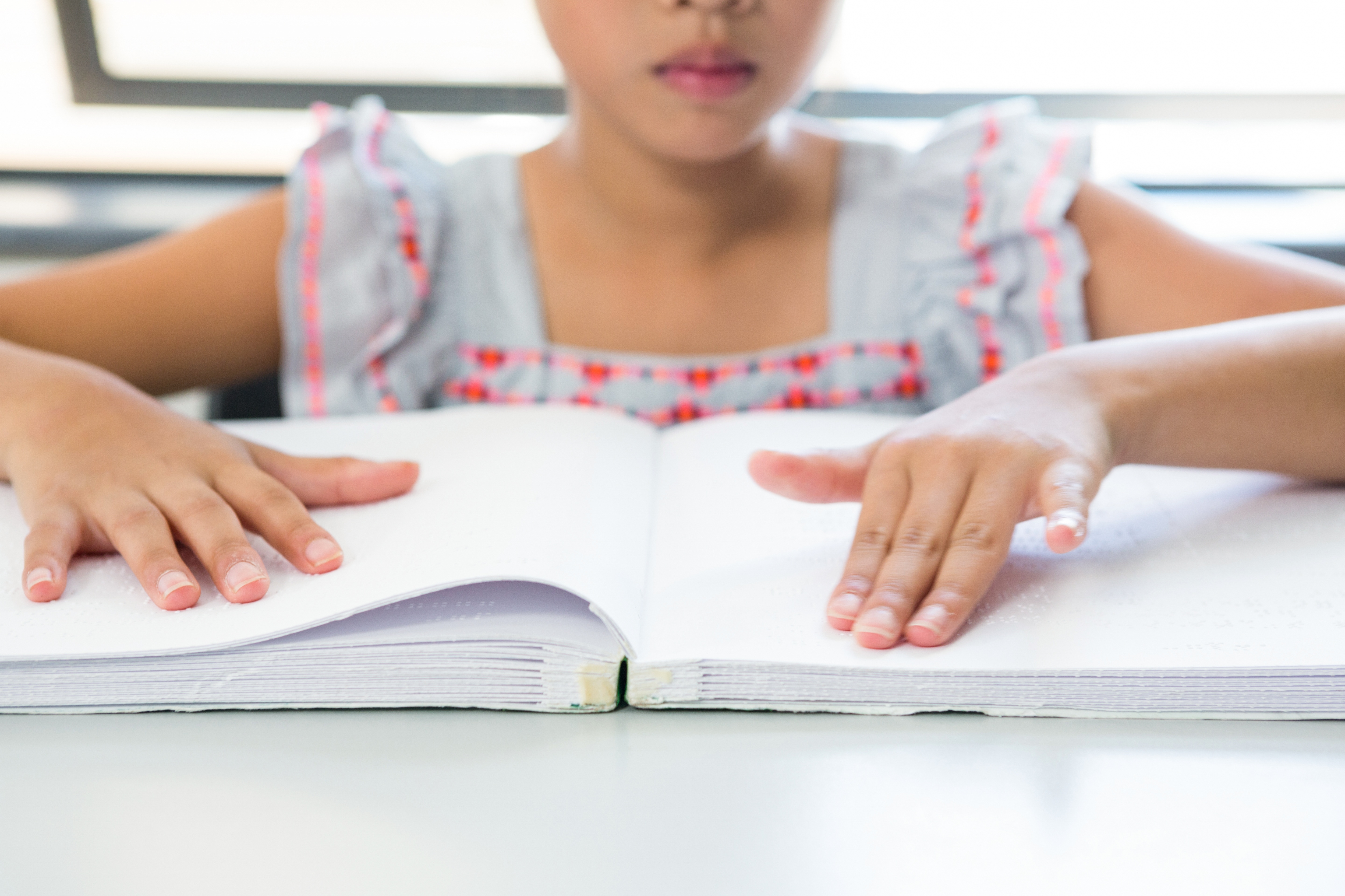 Midsection of girl reading Braille book