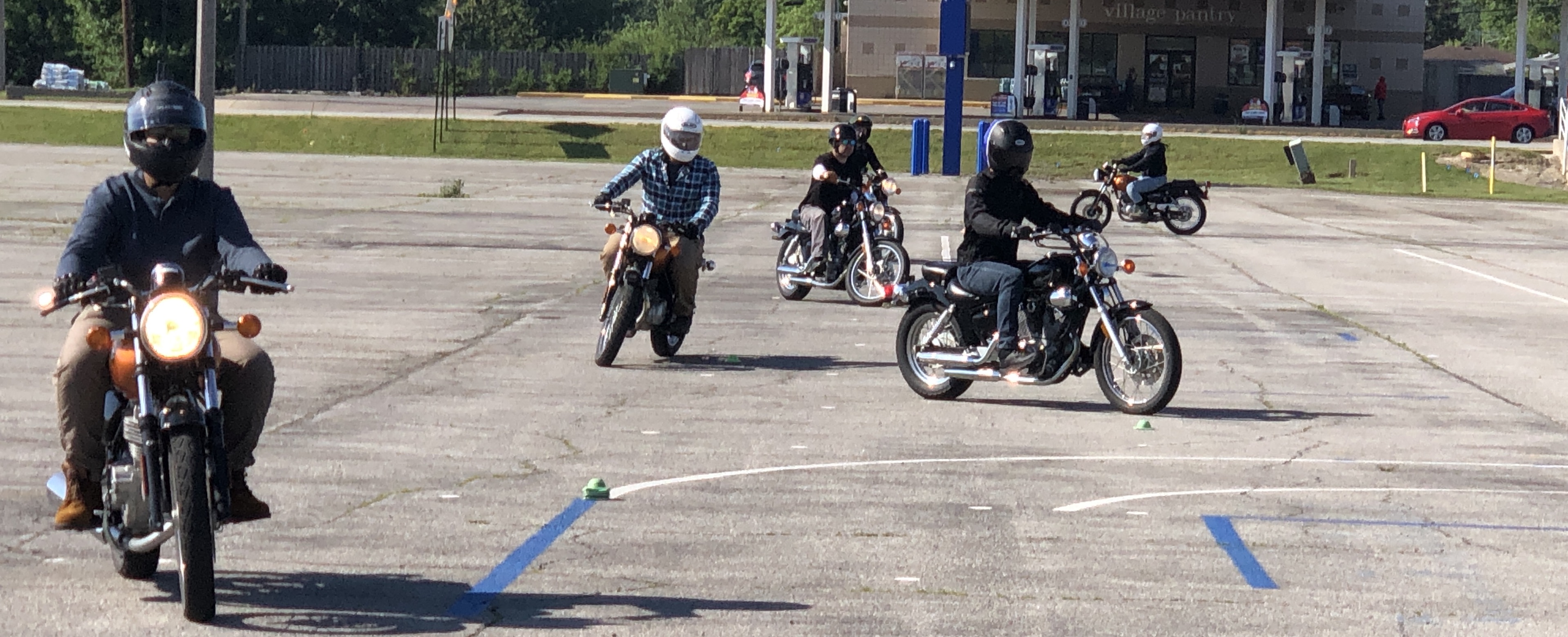six motorcyclists practicing a cone weaver exercise on a closed range