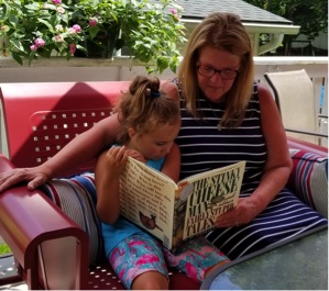 Kenzi reading to Mimi on the glider outdoors.