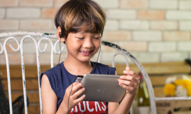 Elementary student wearing earbuds and looking at tablet.