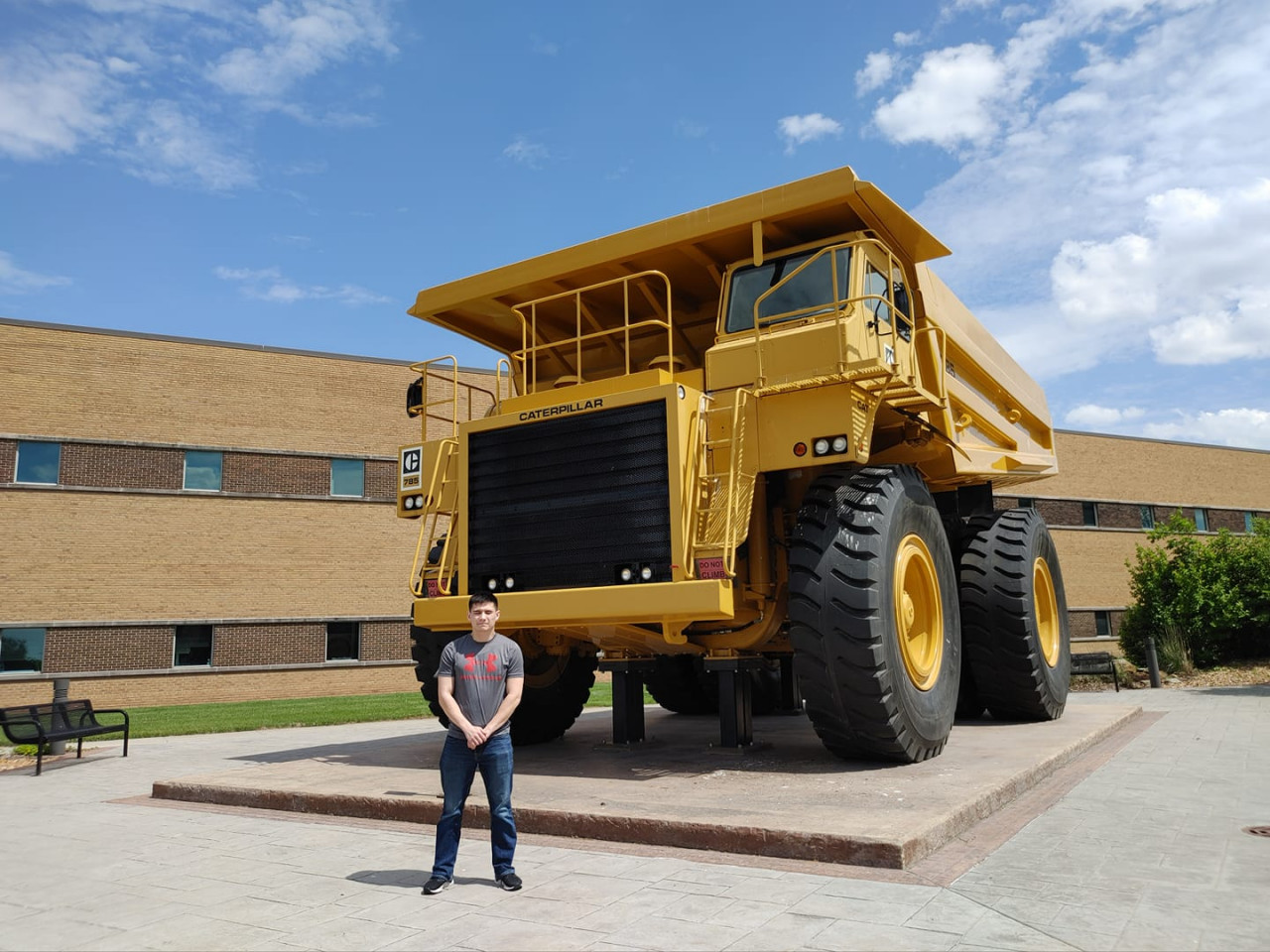 Derek standing in front of a massive Caterpillar dump truck