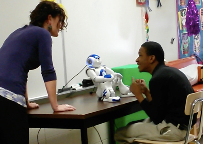 Kelli working with Ophi, the robot, and a student