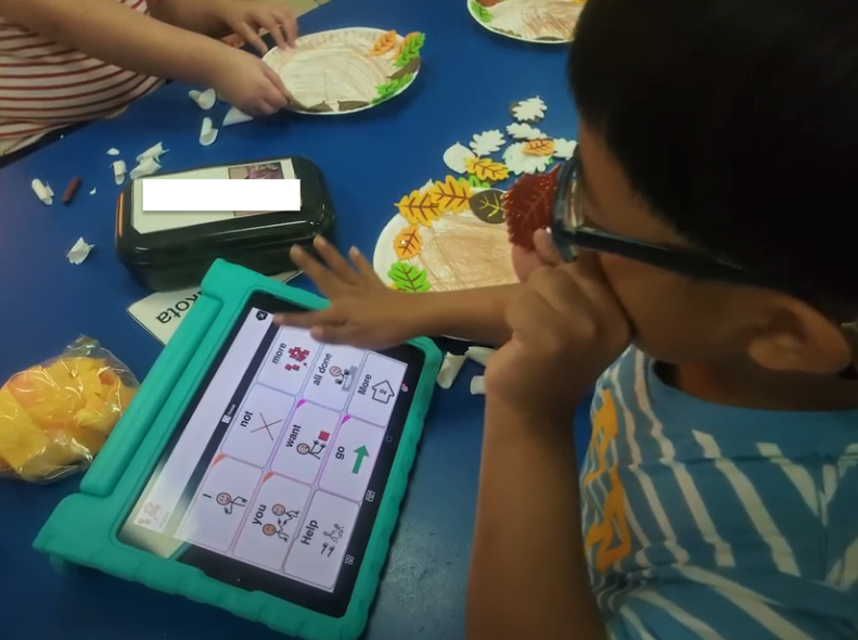 First grader using AAC app on device.