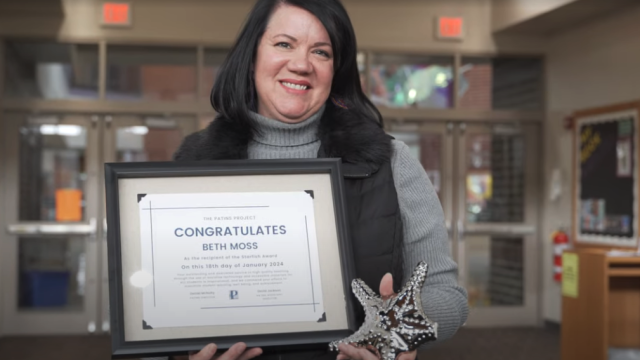 Beth Moss holding framed award certificate and silver starfish